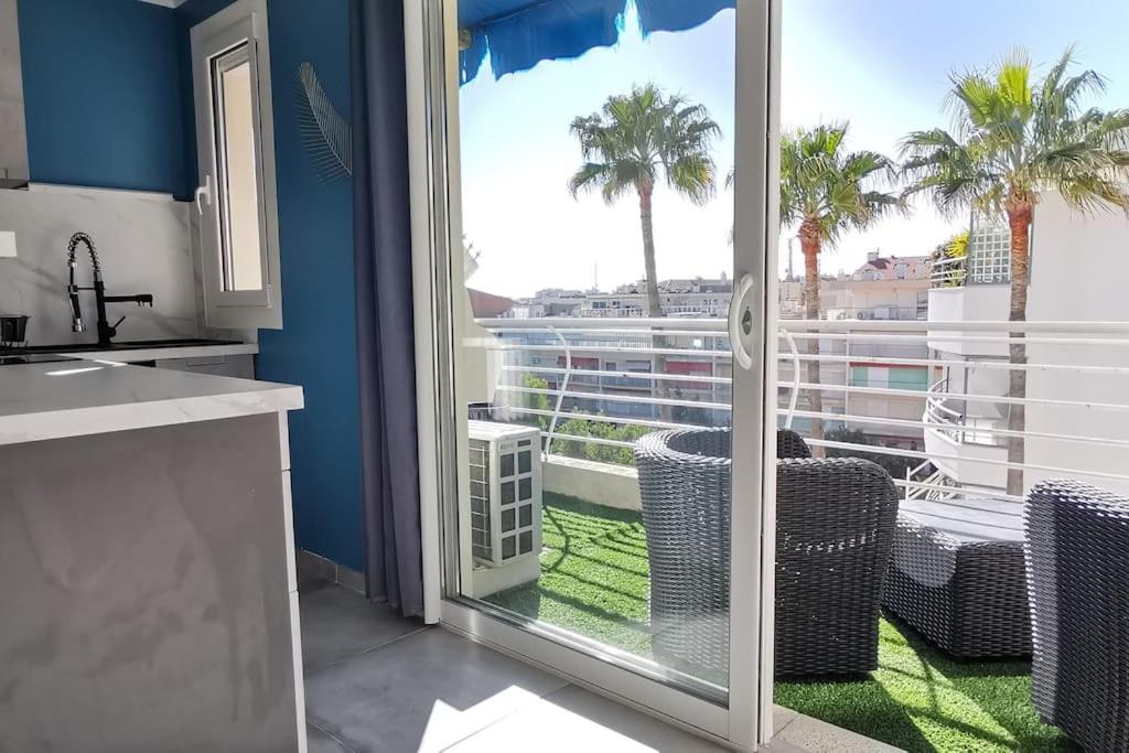 - une cuisine avec vue sur un balcon avec des palmiers dans l'établissement Cannes Pointe Croisette studio plage 2 min à Pieds, à Cannes
