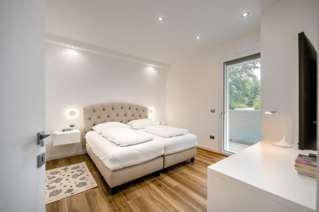 um quarto branco com um sofá branco e uma televisão em Ferrari Apartments Ponente em Caorle
