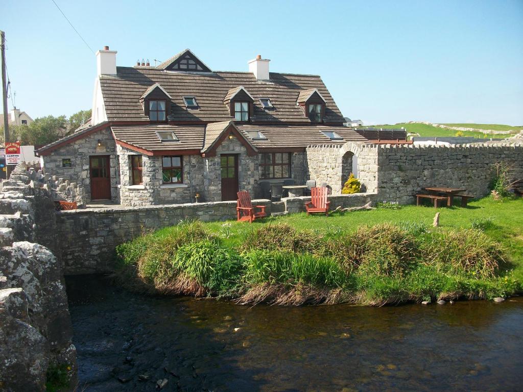 a house sitting on the side of a river at Aille River Tourist Hostel and Camping Doolin in Doolin