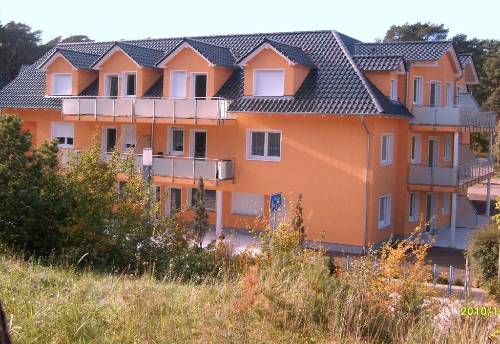 an orange house with balconies on a hill at Apartment zum Dünenblick in Trassenheide