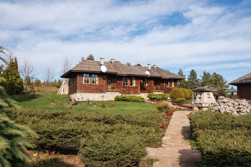 a wooden house in a field with a pathway leading to it at ETNO SELO VRANEŠA Zlatar in Nova Varoš