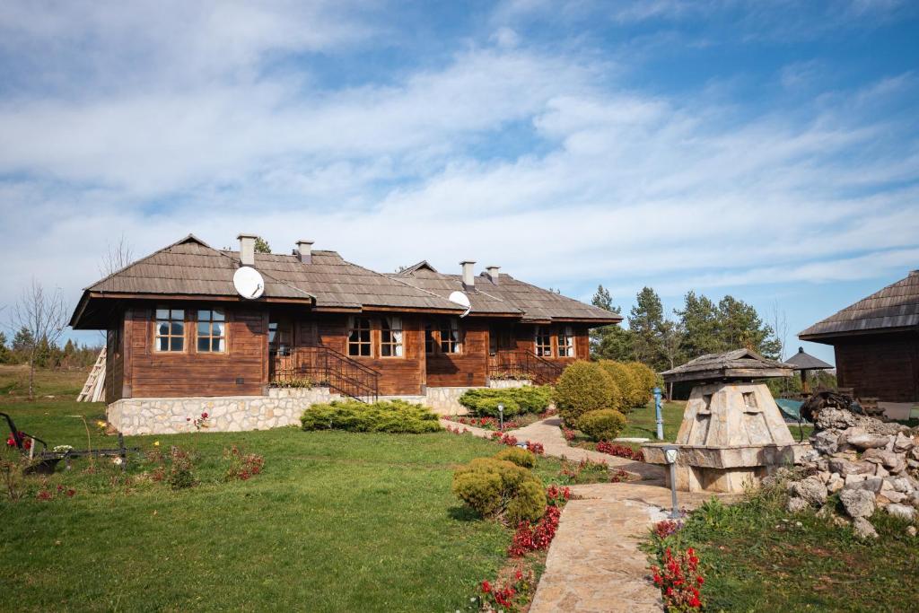 a large wooden house with a grass yard at ETNO SELO VRANEŠA Zlatar in Nova Varoš