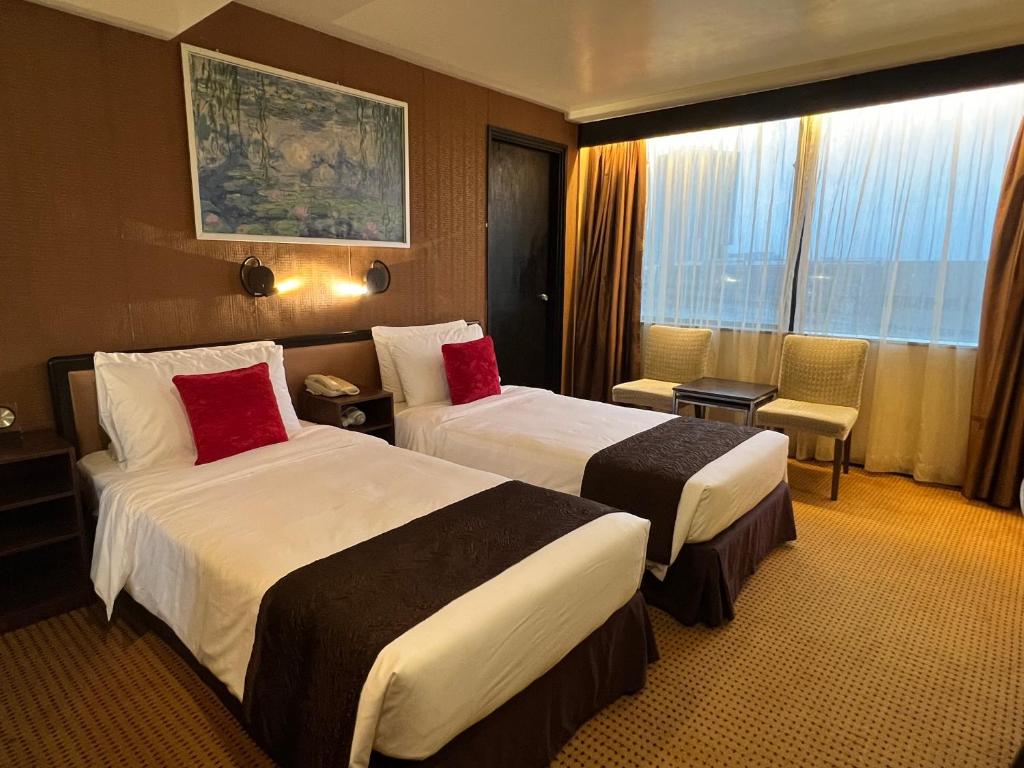 香港にあるベスト ウェスタン プラス ホテル カオルーンのベッド2台と窓が備わるホテルルームです。