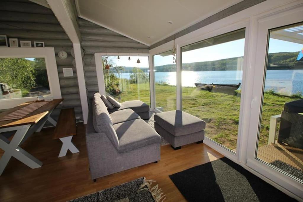 a living room with a couch and a table and windows at Beautiful riverside cottage with sauna in Nuorgam