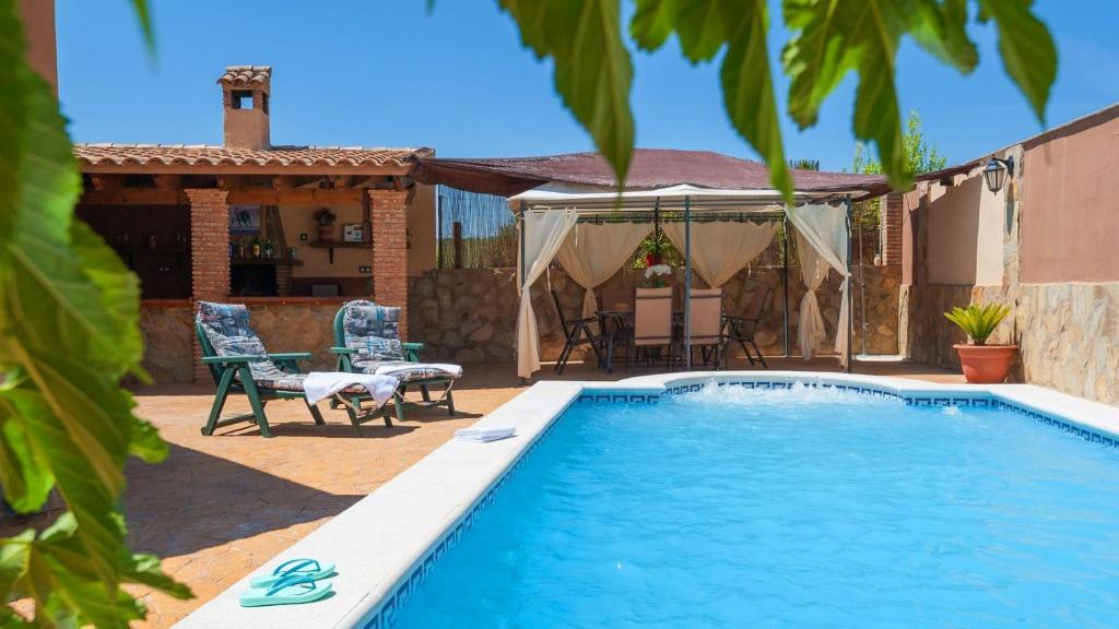 a swimming pool in a yard with a table and chairs at Villa Ortega Alba Alcalá La Real by Ruralidays in Alcalá la Real
