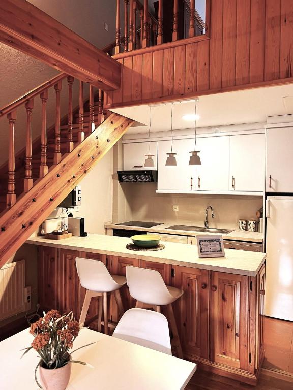 a kitchen with wooden cabinets and a staircase at Arriel 28:24 in Escarrilla