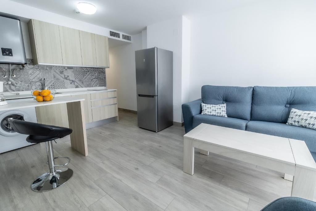a living room with a blue couch and a kitchen at SAN ANDRÉS 13 in Torre del Mar