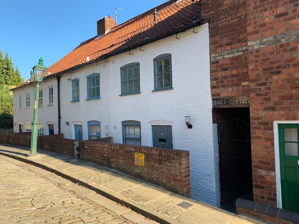 a white building with a brick wall next to a street at 4 Danes Cottages - perfect location in Lincoln