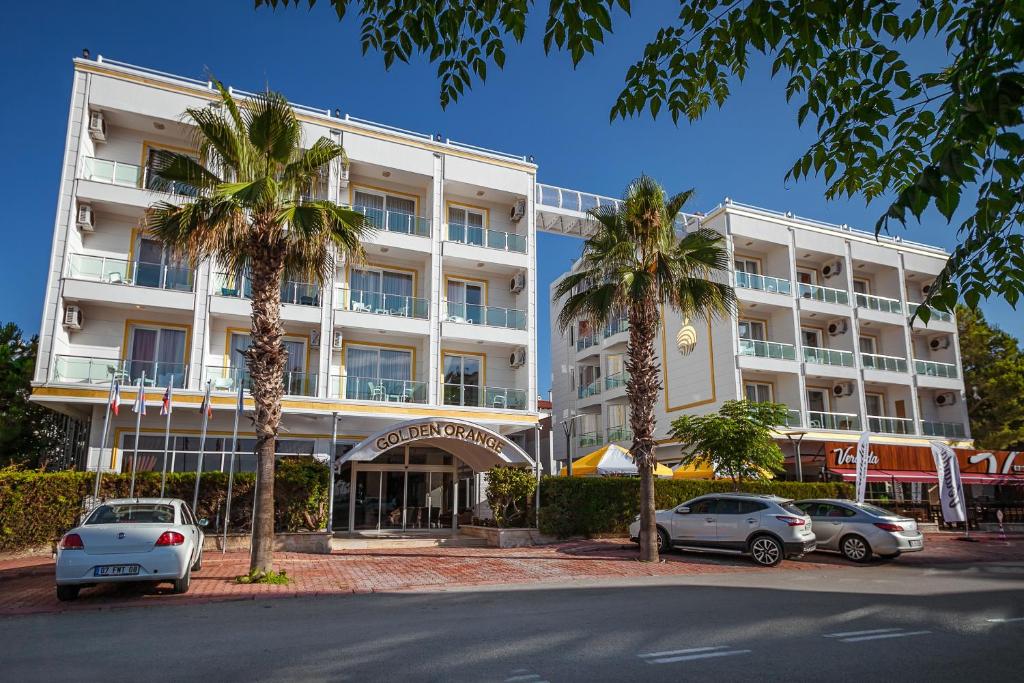 a large white building with cars parked in front of it at Golden Orange Hotel in Antalya