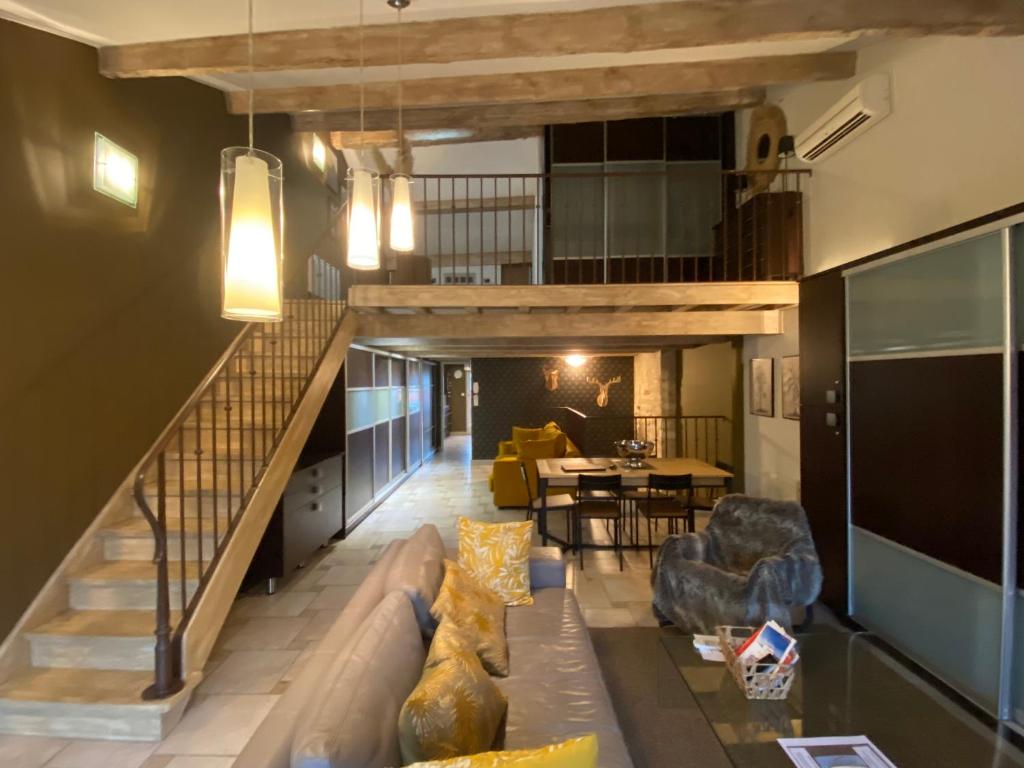 a living room with a couch and a staircase at Le Loft DUPLEX, 2 Terrasses, au coeur du village in Saint-Rémy-de-Provence