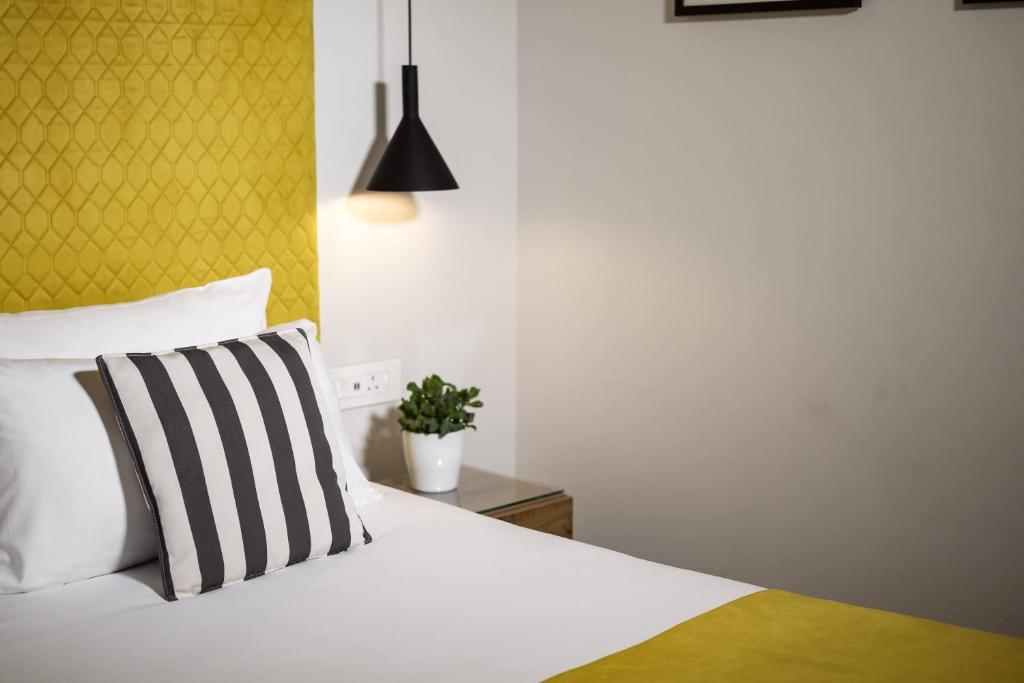 a bedroom with a white bed with a yellow headboard at Urban Rooms by NEU Collective in Il-Gżira