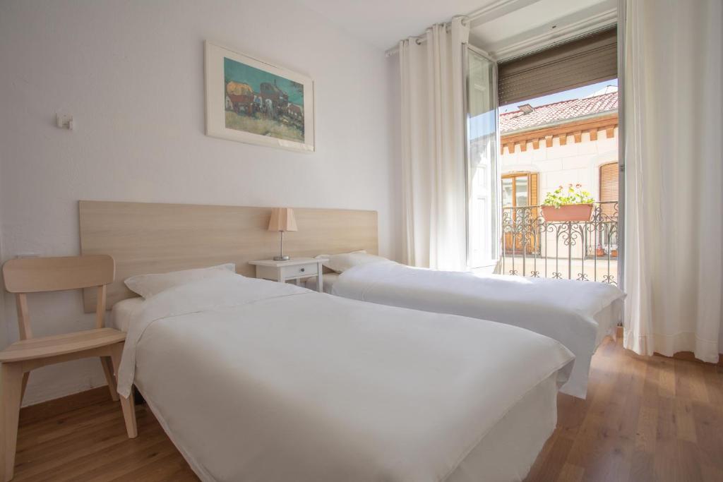 2 camas en una habitación con ventana en NALÓN INN, en Madrid
