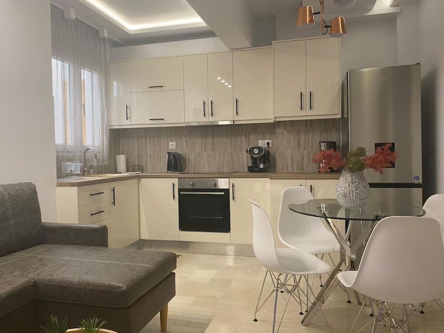 uma cozinha com armários brancos e uma mesa e cadeiras em Apartment by the castle em Ioannina