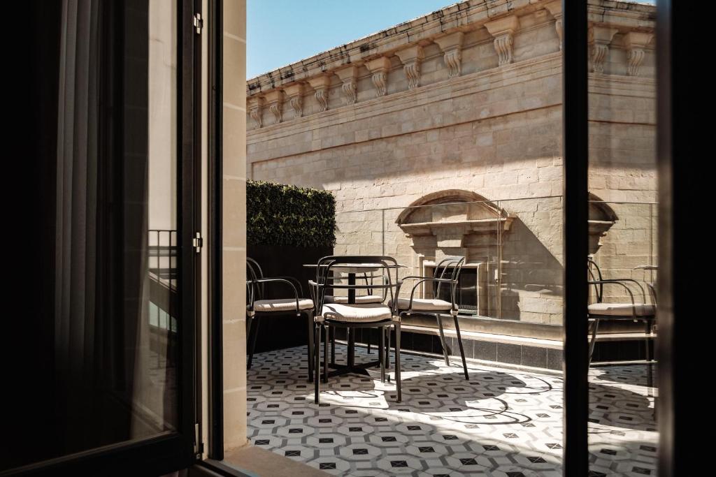 a view from the window of a patio with chairs and a fireplace at The Cumberland Hotel by NEU Collective in Valletta