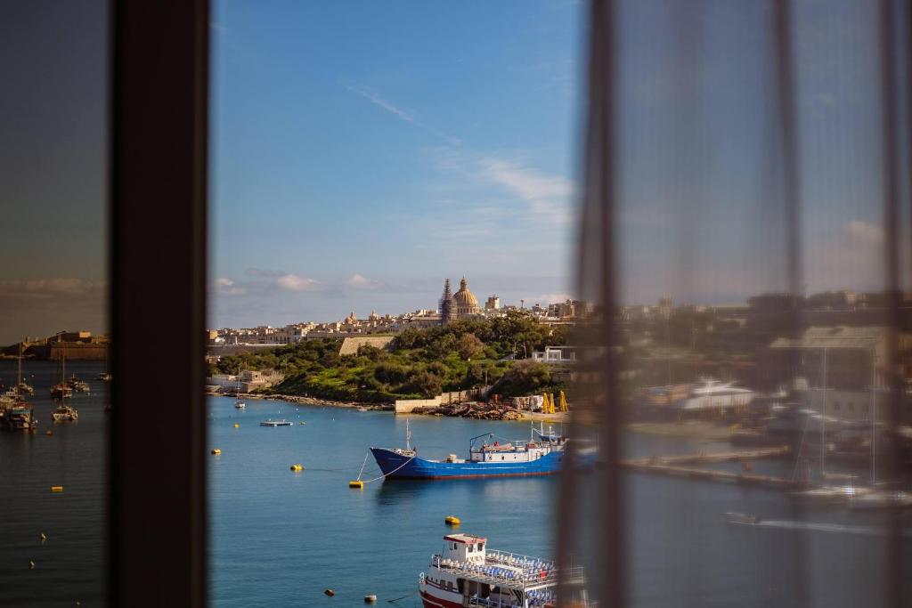 a view of a river with a boat in the water at 115 The Strand Hotel by NEU Collective in Il-Gżira