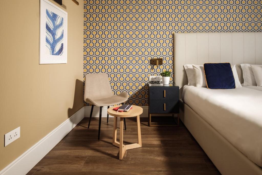 a bedroom with a bed and a chair and a table at 115 The Strand Hotel by NEU Collective in Il-Gżira