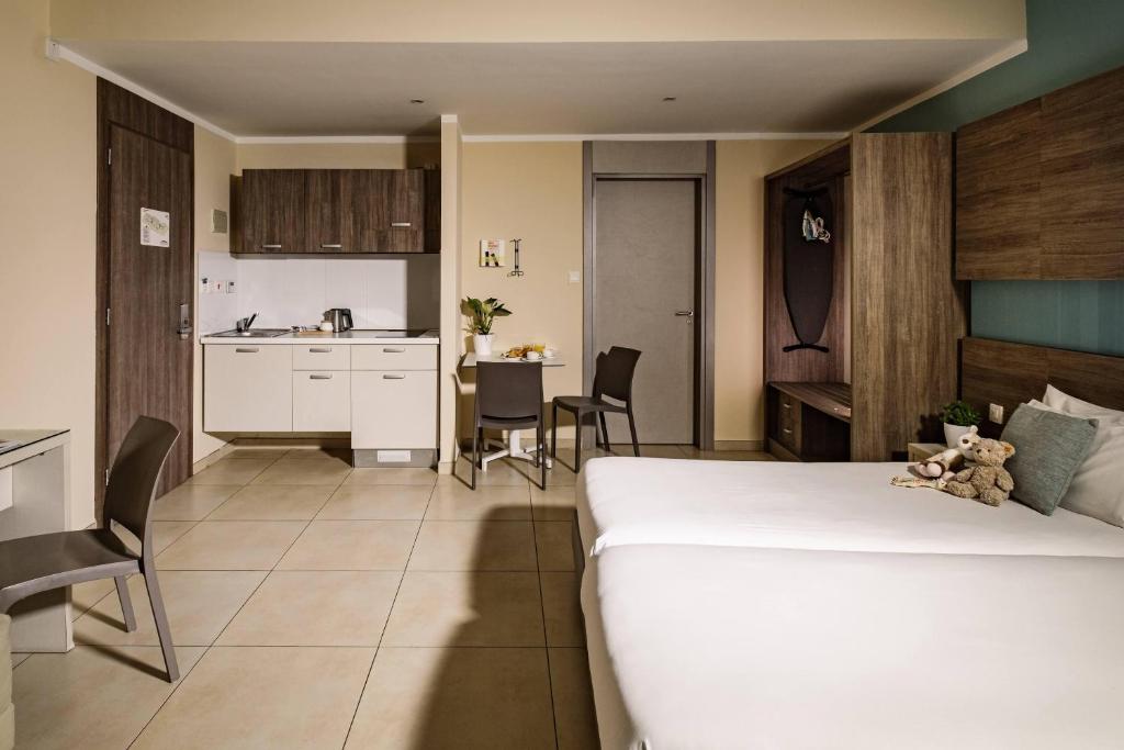 a bedroom with a large white bed and a kitchen at 115 The Strand Hotel by NEU Collective in Il-Gżira