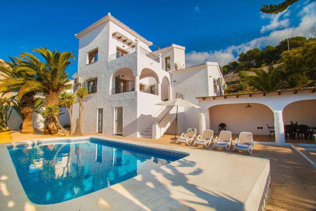 a villa with a swimming pool in front of a house at Villa Ibiza - PlusHolidays in Calpe
