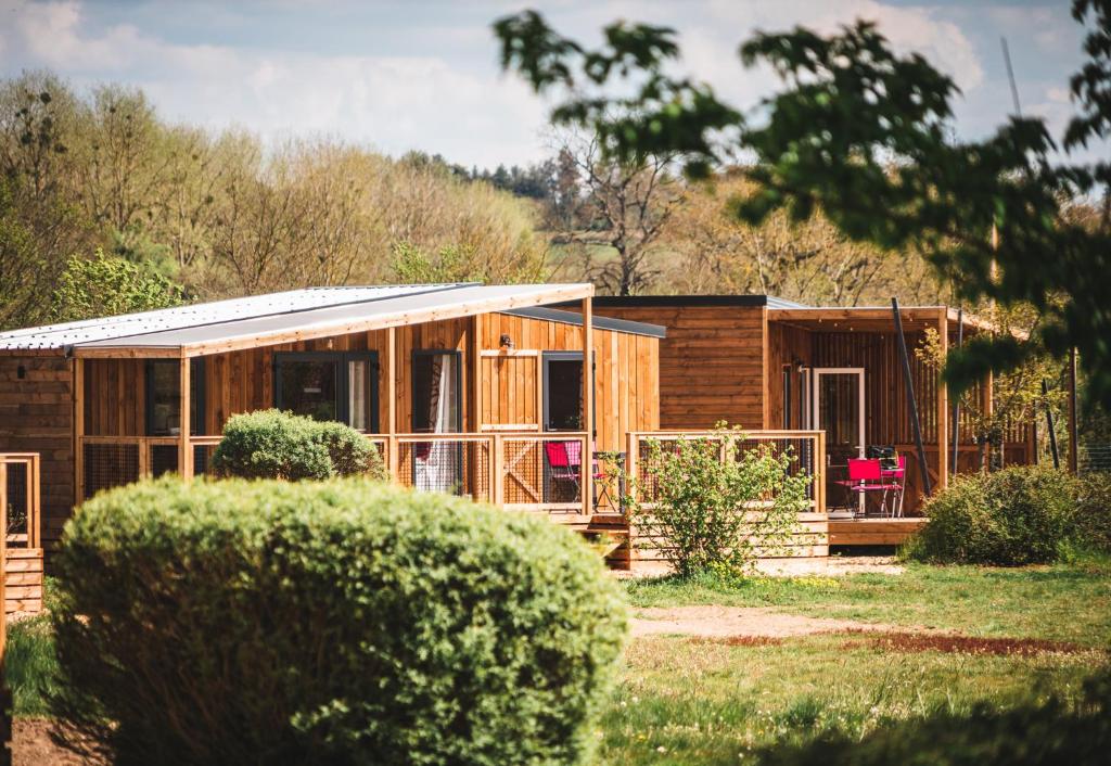 a wooden cabin with a porch in a yard at Le Village de Cottages - Le Pôle du Cheval et de l'Âne in Lignières