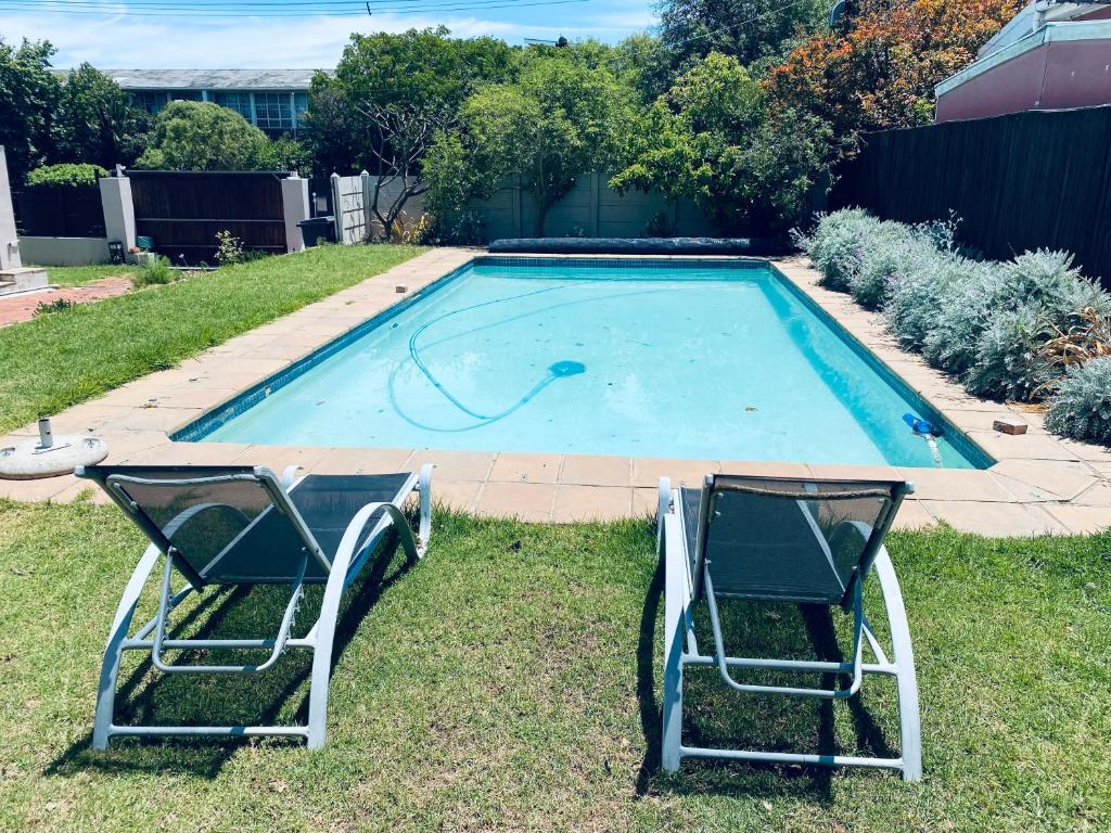 two lawn chairs sitting next to a swimming pool at Studio Flatlet on Montreal in Cape Town