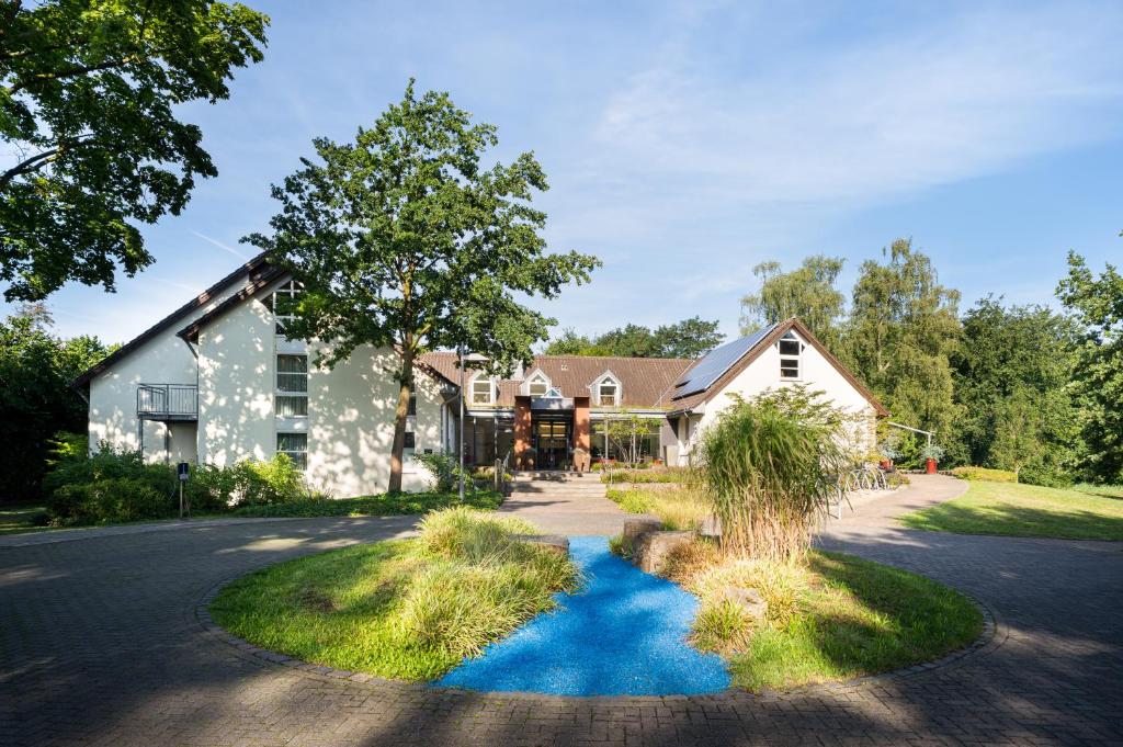 ein Haus mit einem blauen Hof in der Einfahrt in der Unterkunft Flussbett Hotel in Gütersloh