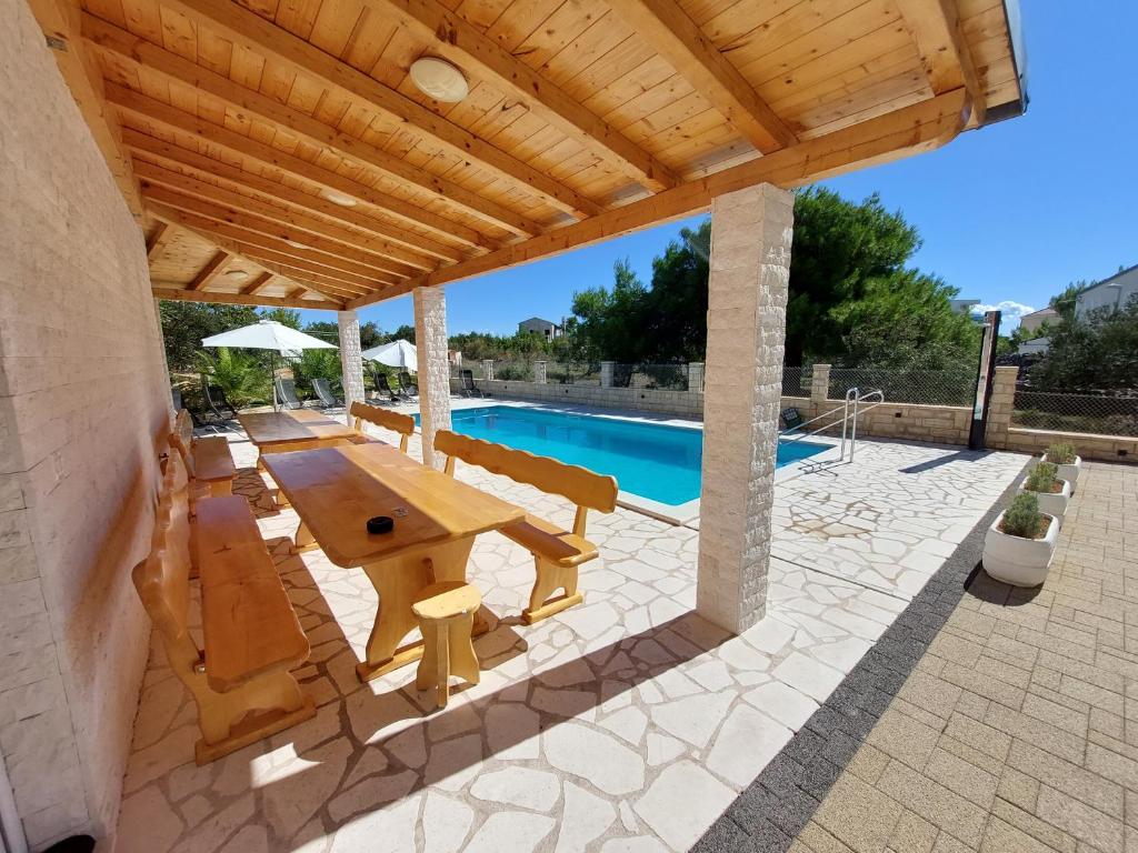 a patio with a table and chairs and a pool at Pranjic Delux Guest House in Vodice