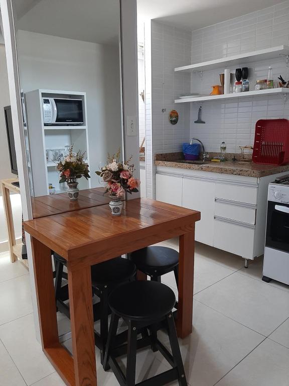 cocina con mesa de madera y algunas sillas en Flat Jardins do Atlântico, frente mar, en João Pessoa