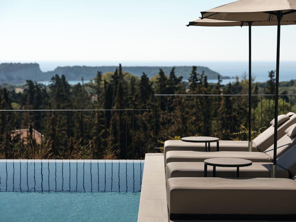 a pool with two lounge chairs and an umbrella at Alexandra SeaView Luxurious Villa, By ThinkVilla in Vasilikos
