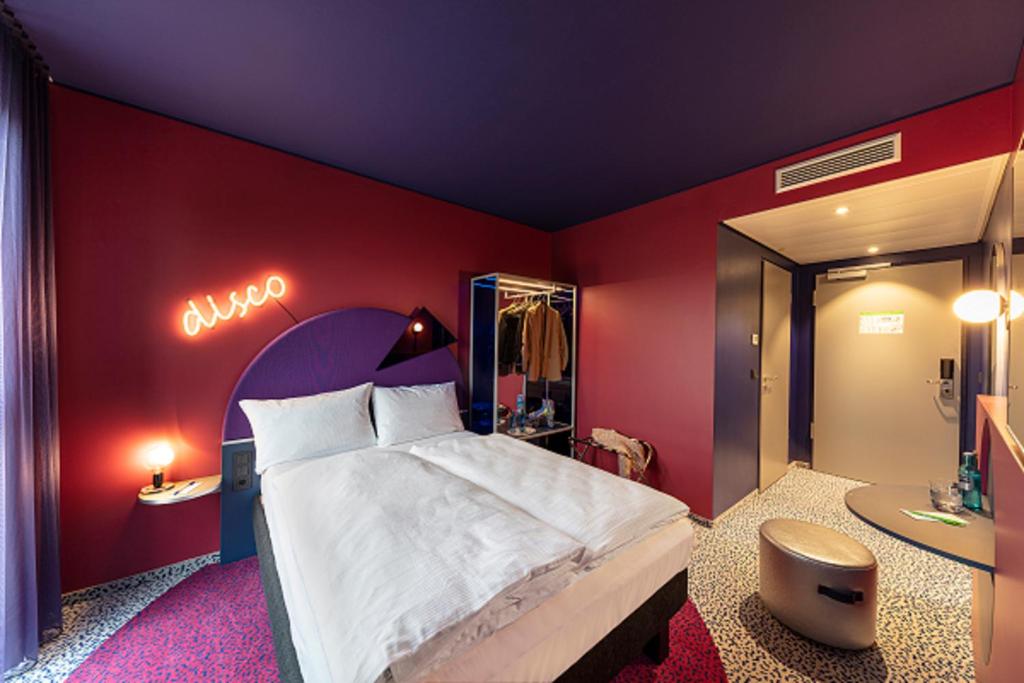 ibis Styles Muenchen Perlach في ميونخ: غرفة نوم بسرير كبير ومرآة