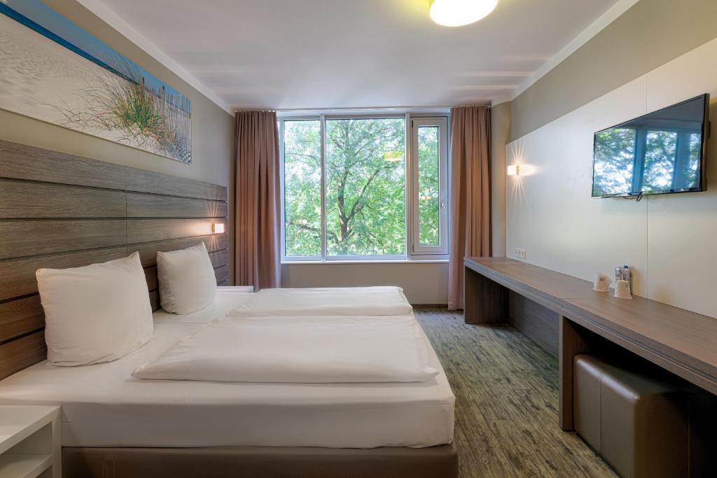 ミュンヘンにあるチューリップイン ミュンヘンメッセのベッド2台と窓が備わるホテルルームです。
