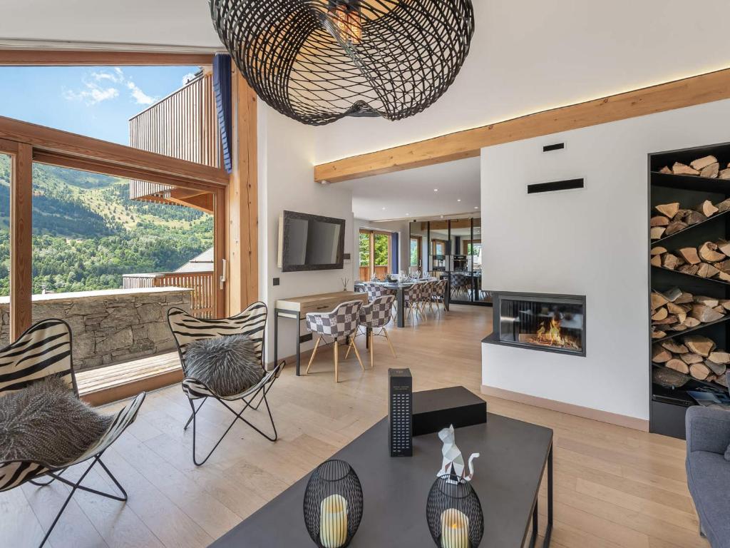 un soggiorno con camino, tavolo e sedie di Chalet moderne à Méribel : jacuzzi, sauna, 6 chambres, proche centre et navette - FR-1-565-55 a Les Allues