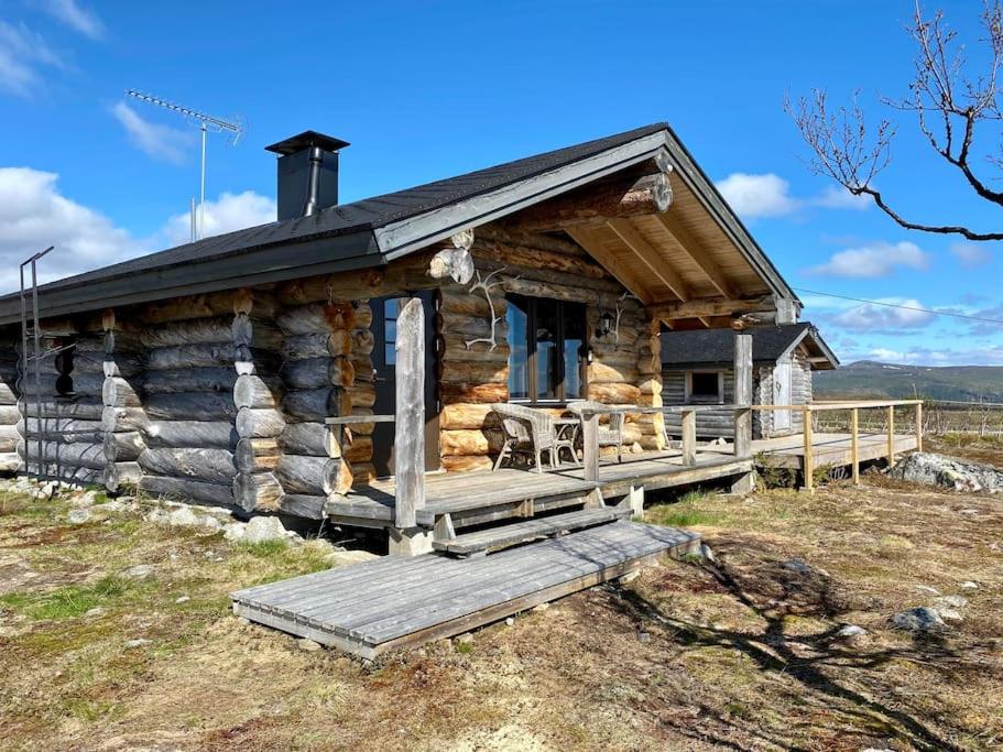 a log cabin on a hill with a wooden porch at Tunturikelo - beautiful log cottage in the Fells in Utsjoki