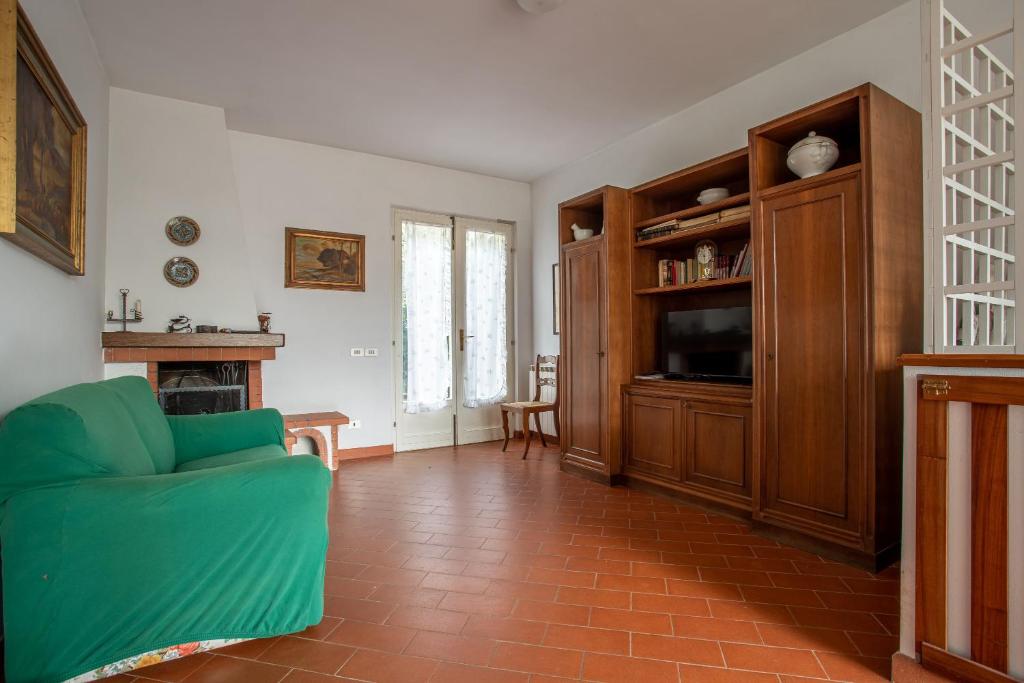 a living room with a green couch and a television at Casa Le Cellane in Castel del Piano