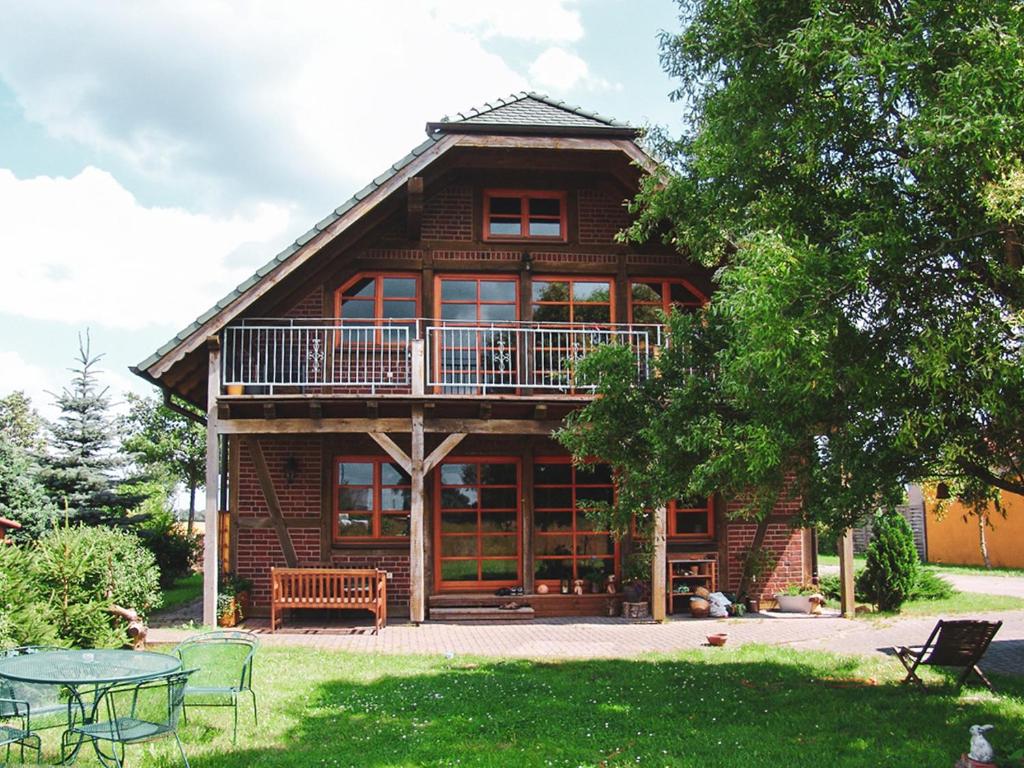 a large wooden house with a balcony and a table at Landhaus Charlotte - Storchennest in Wassersuppe
