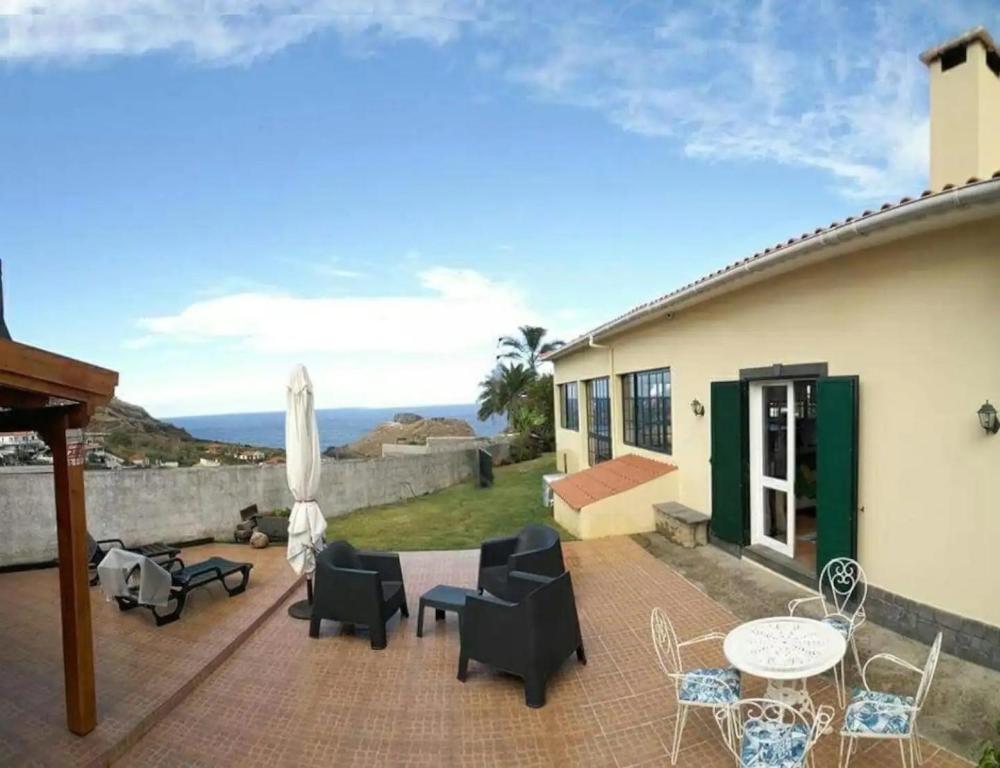 a patio with chairs and tables and an umbrella at House pc in Porto da Cruz
