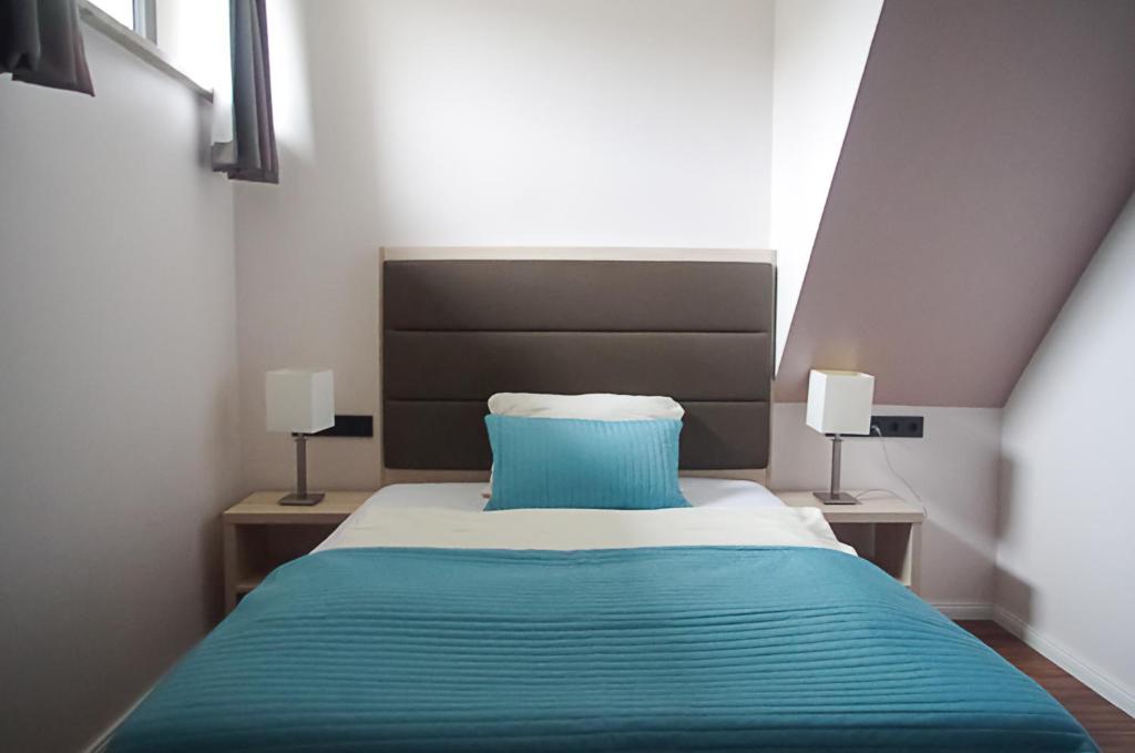 1 dormitorio con 1 cama azul y 2 lámparas en Gothmann´s Hotel, en Breitenfelde