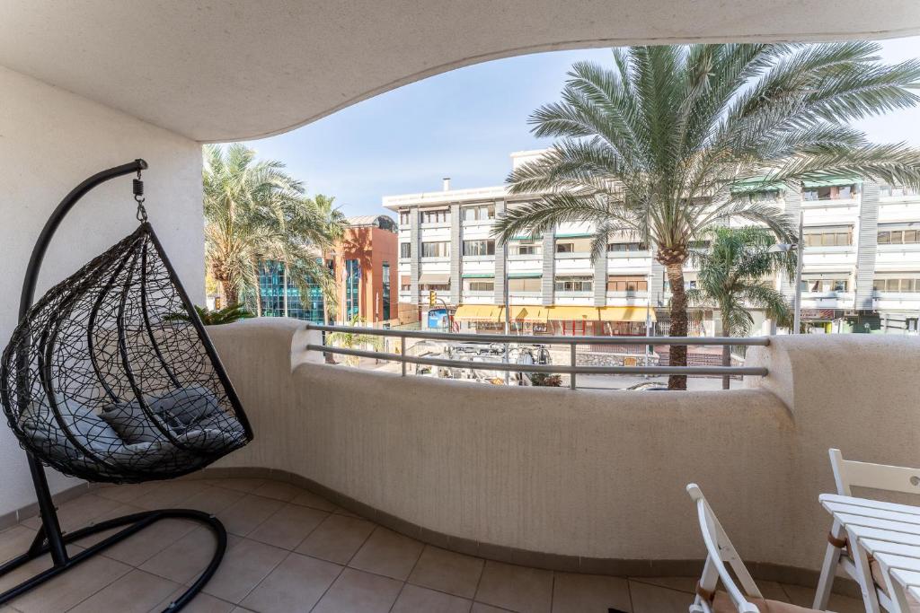 a balcony with a hammock and a palm tree at Spacious 2bed family apartment in Puerto Marina in Benalmádena