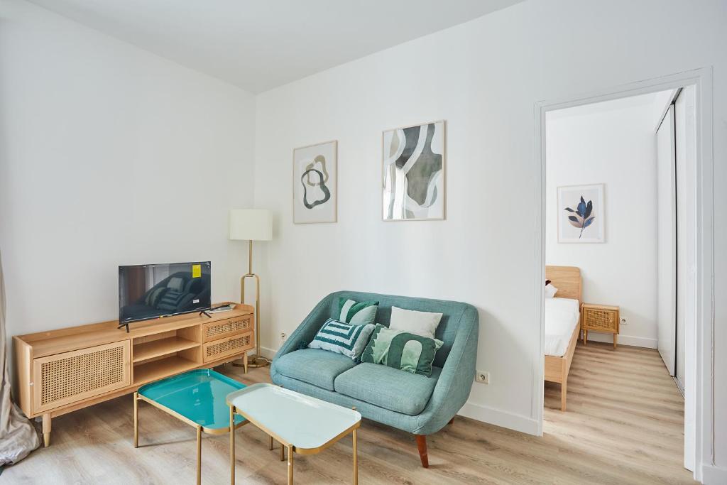 un salon avec une chaise bleue et une télévision dans l'établissement Residence Neuilly Bois de Boulogne by Studio prestige, à Neuilly-sur-Seine