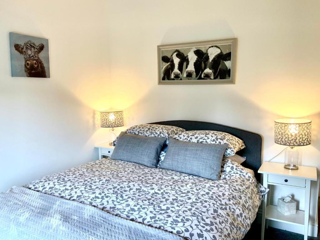 a bedroom with a bed with two lamps and pictures on the wall at Quality Oak Barn with Hot Tub and Parking in Bramley