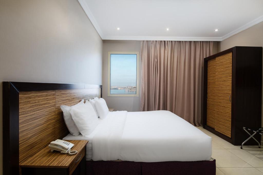 Un dormitorio con una cama blanca y un teléfono en un escritorio. en Mirada Purple Obhur - Serviced Apartments, en Yeda