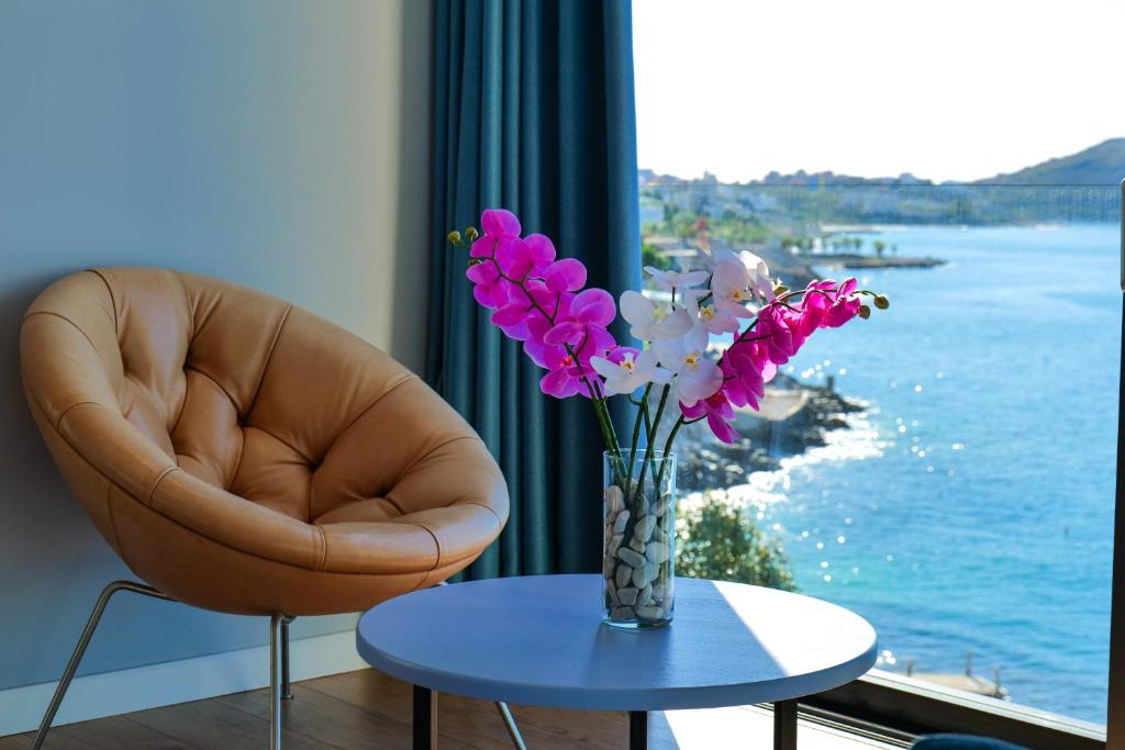 eine Vase mit Blumen auf einem Tisch vor einem Fenster in der Unterkunft Hotel Nertili in Sarandë