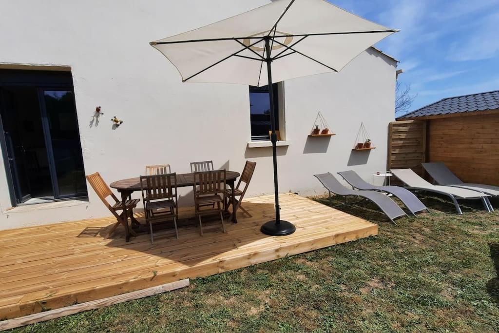 um deque de madeira com uma mesa e um guarda-chuva em Maison lumineuse avec jardin em Néffiès