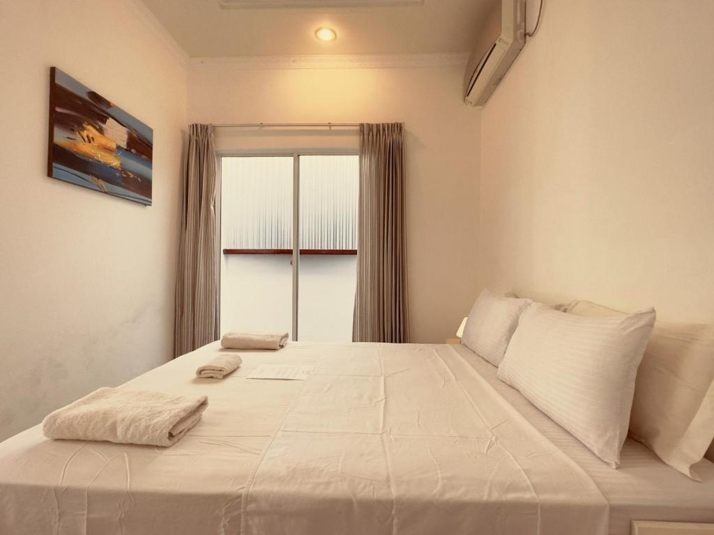 a bedroom with a large white bed with a window at Vaali Maldives Island Escapes & Dive in Felidhoo