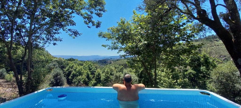 Un uomo in piedi in una piscina che guarda le montagne di Quinta Pomar Do Pontido a Cabeceiras de Basto