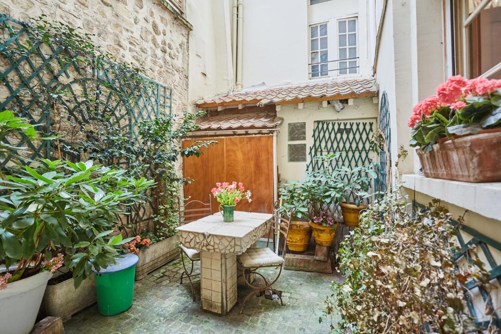 a small patio with a table and potted plants at Apartment in heart of Marais by Studio prestige in Paris