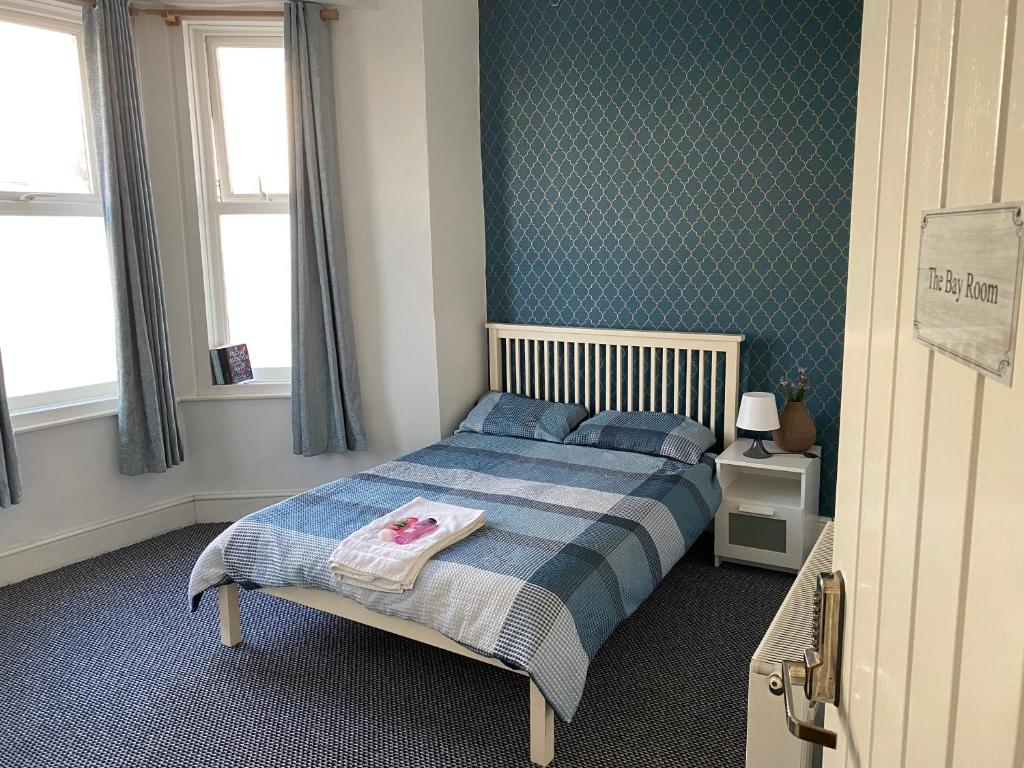 a bedroom with a bed with a blue and white blanket at The Bay En-suite Room in Plymouth