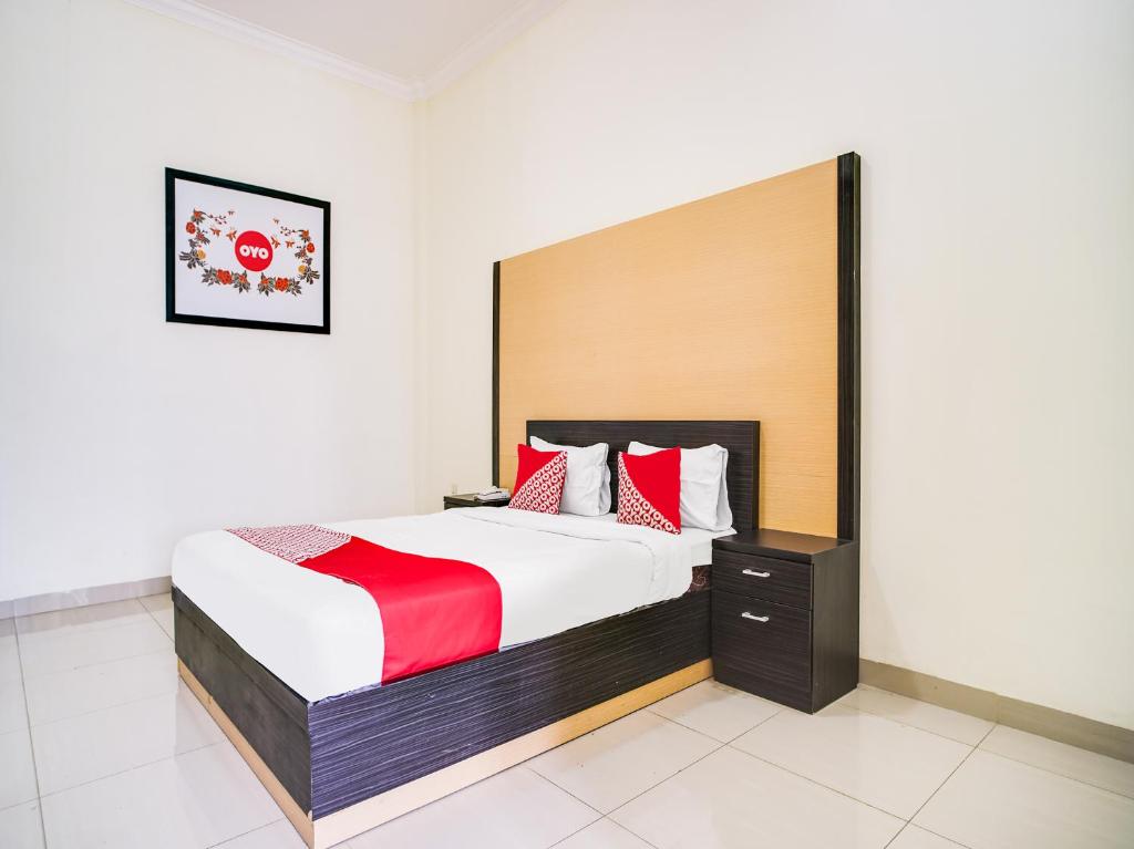 a bedroom with a large bed with red and white pillows at SUPER OYO Capital O 540 Esther Hotel in Balige