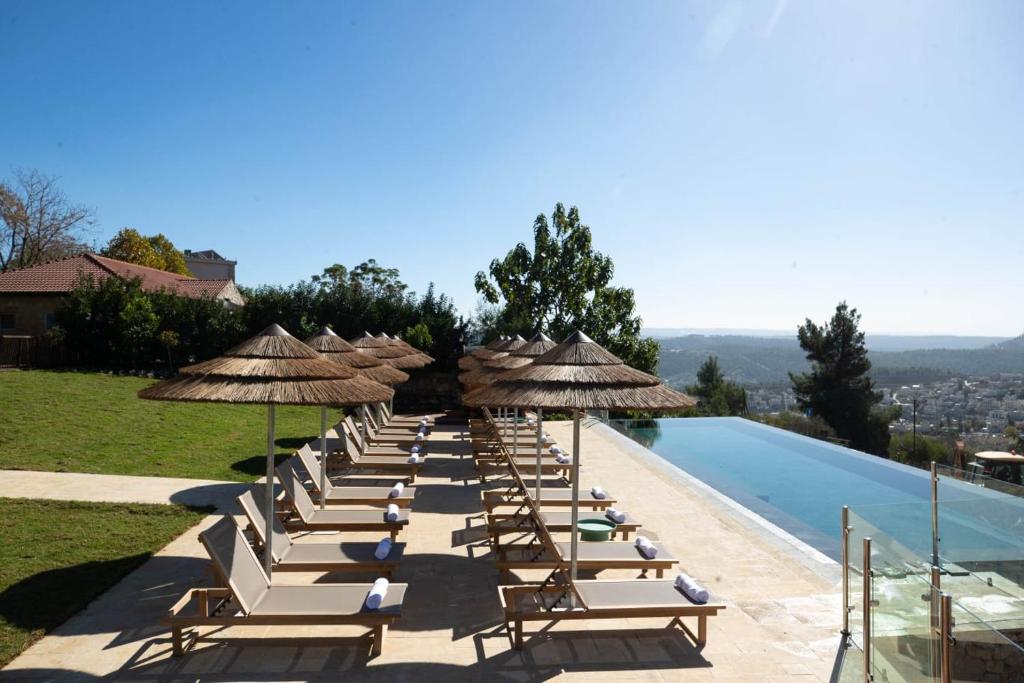 una fila de sillas y sombrillas junto a una piscina en Gordonia Private Hotel en Maale Hachamisha