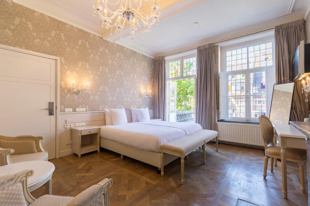 a bedroom with a bed and a chandelier at Amrâth Hotel Bigarré in Maastricht