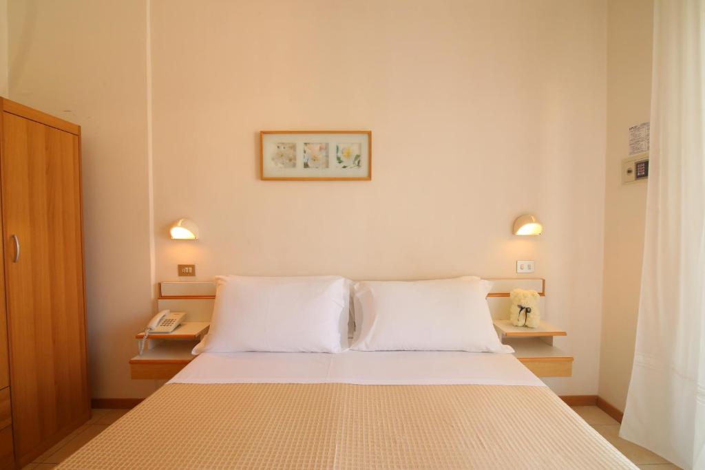 una camera con un letto con due cuscini bianchi di Hotel Soave a Rimini